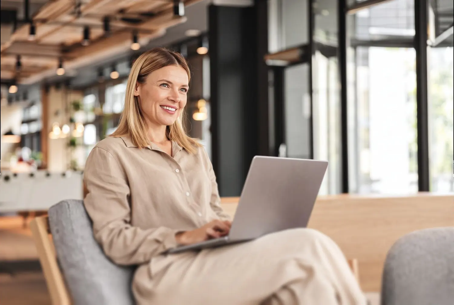 Executiva sorrindo enquanto trabalha no notebook em um escritório claro